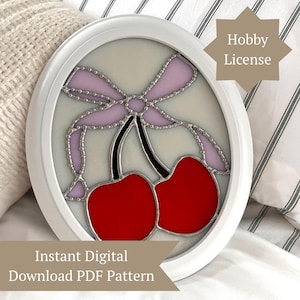 May include: A white framed stained glass piece featuring two red cherries with black stems and a light purple bow. The text "Instant Digital Download PDF Pattern" is at the bottom, and "Hobby License" is in the upper right corner.