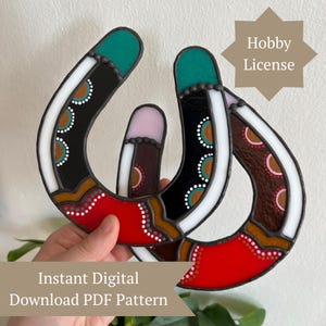 Puede incluir: Una obra de arte en vidriera con forma de herradura estilizada, con secciones rojas, negras y marrones, y detalles blancos y turquesas. El texto "Instant Digital Download PDF Pattern" es visible. La imagen también incluye el texto "Hobby License".
