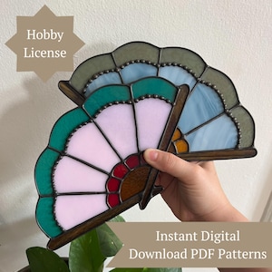 May include: A stained glass fan-shaped object featuring panels of light pink, dark red, teal, and light blue glass held together by dark metal soldering. The text Hobby License and Instant Digital Download PDF Patterns is visible.