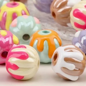 May include: Assortment of colorful round beads with various patterns and designs. The beads are made of plastic and have a glossy finish. They are perfect for crafting jewelry, making bracelets, necklaces, and other accessories.