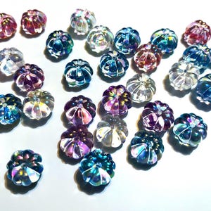 May include: Assortment of iridescent glass pumpkin-shaped beads in various colors, including pink, blue, purple, and clear.