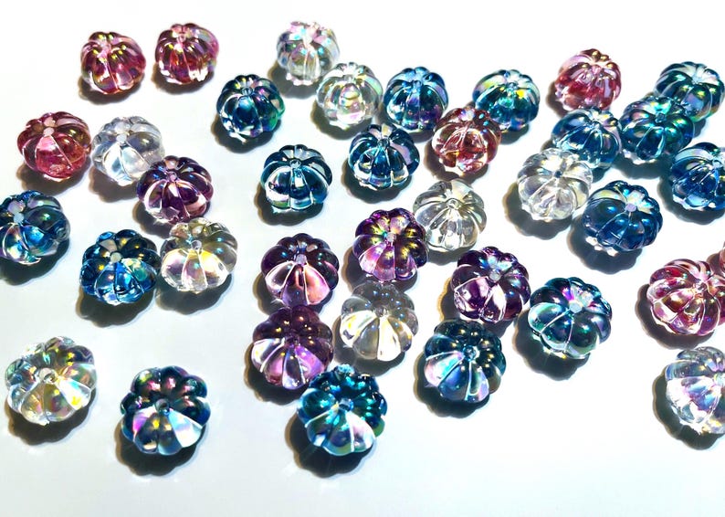 May include: Assortment of iridescent glass pumpkin-shaped beads in various colors, including pink, blue, purple, and clear.