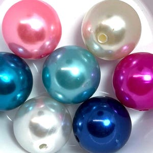May include: Seven large, round, pearl-like beads in various colors, including pink, white, teal, blue, and magenta.