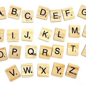 Könnte beinhalten: Ein Satz hölzerner Buchstabenkacheln mit schwarzer Beschriftung, die für das Spiel Scrabble verwendet werden. Die Kacheln sind alphabetisch geordnet, wobei jede Kachel den Buchstaben und seinen Punktwert zeigt.