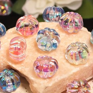 May include: A collection of iridescent glass pumpkin beads in various shades of pink, blue, and purple. The beads have a textured surface and are perfect for crafting.