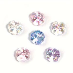 May include: Six iridescent glass pumpkin beads in shades of pink, blue, and white. The beads are approximately 1 inch in diameter and have a slightly textured surface.