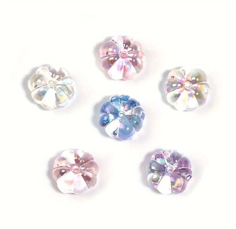 May include: Six iridescent glass pumpkin beads in shades of pink, blue, and white. The beads are approximately 1 inch in diameter and have a slightly textured surface.