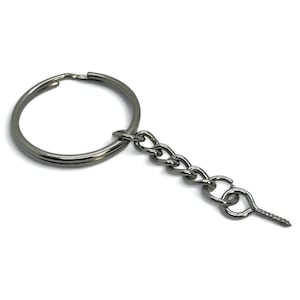 May include: A silver-colored keychain with a split ring, chain, and screw eyelet. The split ring is circular, and the chain is made of small, interconnected links. The screw eyelet is at the end of the chain.