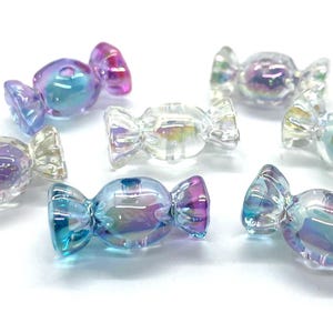 May include: Assortment of iridescent candy-shaped glass beads in shades of blue, purple, and pink. The beads are designed to resemble wrapped candies.