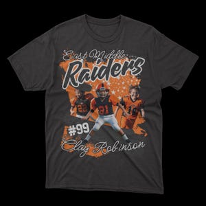May include: A dark grey t-shirt with an orange and white design. The design features the text "East Middle Raiders" with a football player in the centre. The text "#99 Clay Robinson" is below the image.