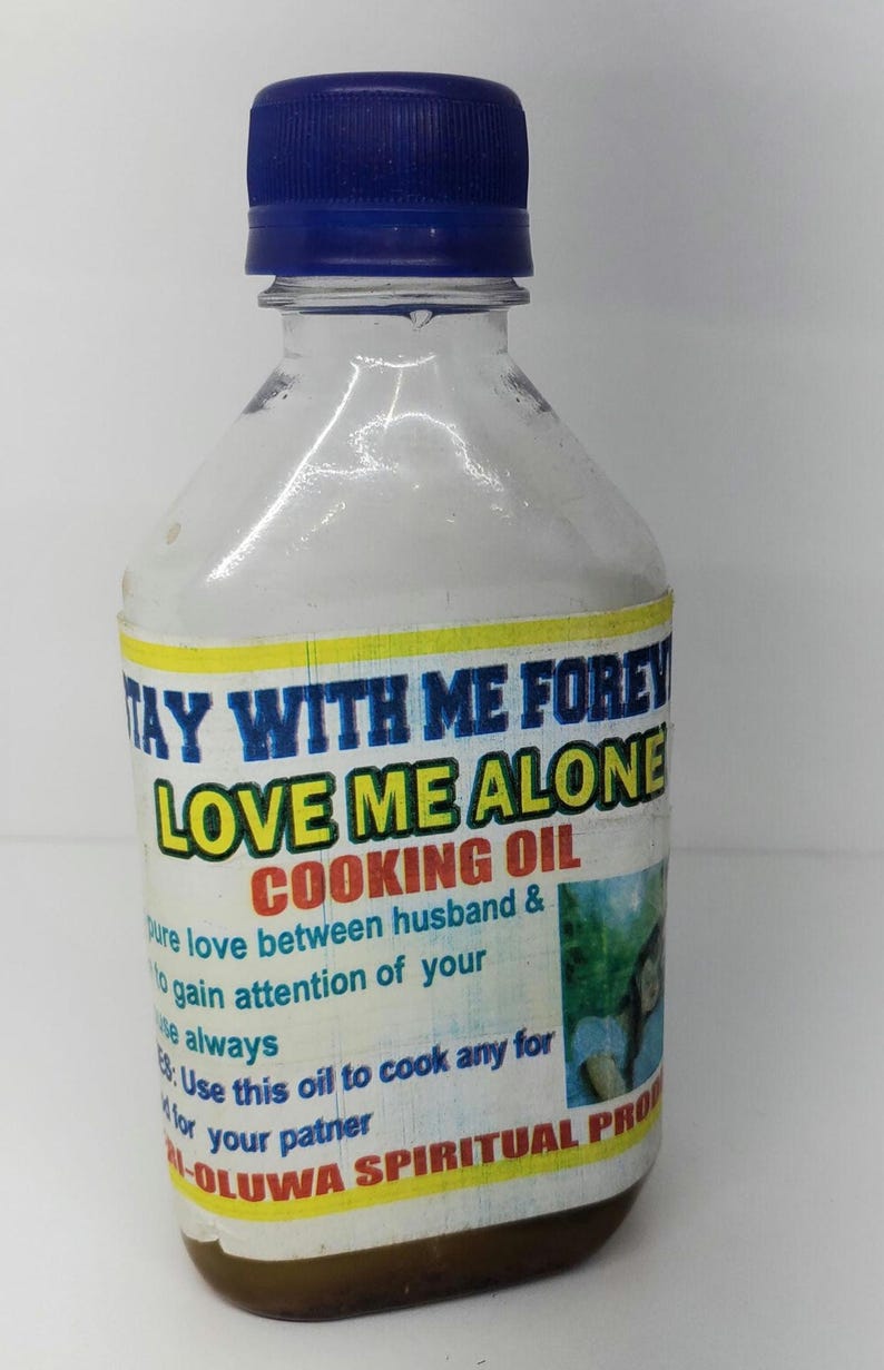 May include: A clear glass bottle with a blue cap and a yellow label that reads "Stay With Me Forever Love Me Alone Cooking Oil". The label also includes the text "Use this oil to cook any for your partner" and "Oluwa Spiritual Products".