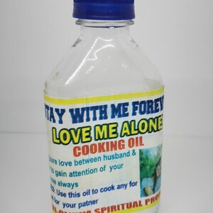 May include: A clear plastic bottle with a blue cap and a yellow label that reads "Stay With Me Forever Love Me Alone Cooking Oil". The label also includes the text "Pure love between husband & to gain attention of your Use this oil to cook any for your partner M-Oluwa Spiritual Products".