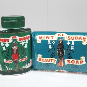 May include: A green talcum powder bottle and a teal soap bar, both labeled "Bint El Sudan." The bottle features a woman in a red skirt, while the soap has a woman in a black dress. Both have floral accents.