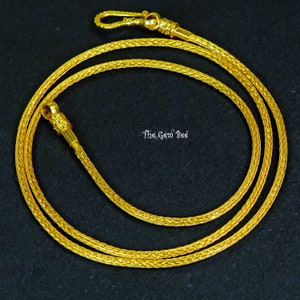 Può includere: Una collana a catena d'oro con un design intrecciato e una chiusura a moschettone.