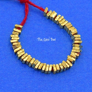 May include: A gold-colored chain made of rectangular links. The chain is strung on a red string.