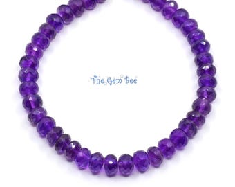 May include: A strand of faceted, deep purple amethyst gemstone beads arranged in a circular shape. The beads are strung on a thin cord, and the text The Gem Bee is printed in blue in the center of the circular arrangement of beads.