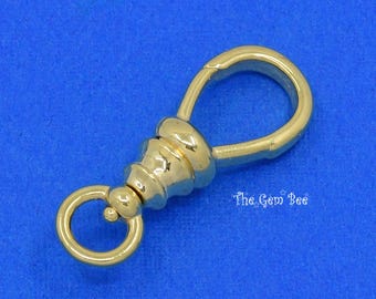 May include: A gold-toned metal swivel lobster claw clasp featuring a smooth, polished finish. The hardware includes a teardrop-shaped loop at one end and a smaller circular ring at the base, with the text The Gem Bee printed in white.