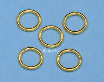 Könnte beinhalten: Fünf kreisförmige goldfarbene Biegeringe, die in einem fünfeckigen Muster angeordnet sind. Jeder Ring weist eine sichtbare Naht auf, an der die Enden aufeinandertreffen. Der Text The Gem Bee ist weiß in der Mitte dieser Schmuckkomponenten gedruckt.