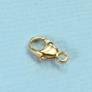 May include: Gold-toned metal clasp with a spring-loaded closure and a small loop. This clasp is commonly used for necklaces, bracelets, and other jewelry.