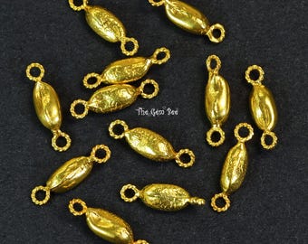May include: A collection of eleven gold-toned metal jewelry connectors, each featuring a central oval-shaped bead with a textured surface and a small twisted loop at both ends. The text The Gem Bee is printed in the center of the arrangement.