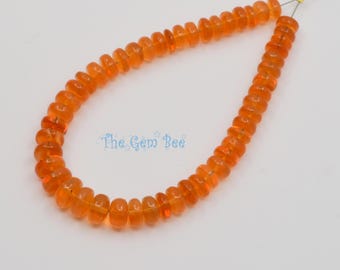 May include: A strand of translucent orange rondelle-shaped beads arranged in a U-shape on a thin wire. The beads have a smooth, polished finish and a consistent vibrant color. The text The Gem Bee is printed in light blue in the center.
