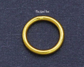 May include: A single circular gold jump ring with a smooth, polished finish. The metal ring is uniform in thickness and features a small, visible seam where the ends meet. The text The Gem Bee is printed in white above the gold ring.
