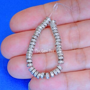 May include: A strand of silver-toned beads with clear rhinestones. The beads are round and have a small hole in the centre. The beads are strung on a clear elastic cord.