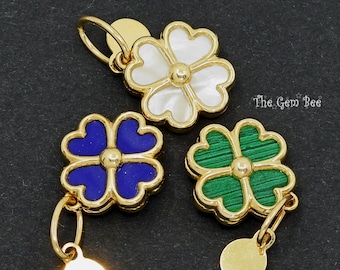 May include: Three gold-toned metal charms shaped like four-leaf clovers, featuring white, blue, and green inlaid centers. Each charm has a small circular gold tag attached. The text The Gem Bee is visible on the right side of the image.
