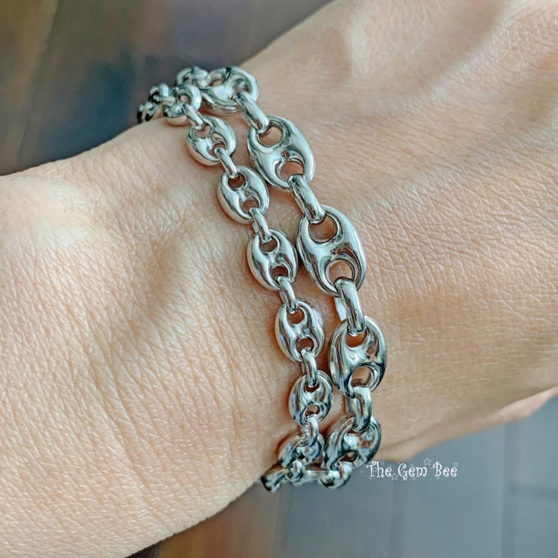 May include: Two silver-toned chain bracelets with a unique link design. The bracelets are worn together, showcasing the intricate details of the links. The Gem Bee is printed on the bottom right.
