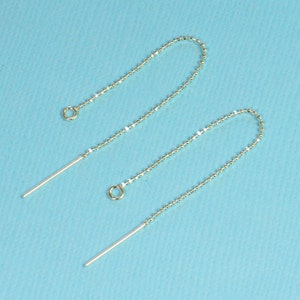 May include: Two silver earring extenders with a small loop at the top and a long, straight, silver post at the bottom.