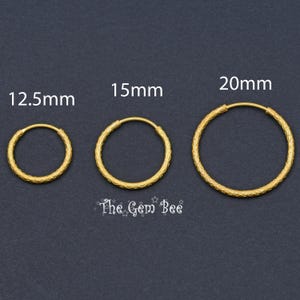 Puede incluir: Tres aros dorados con superficie texturizada, etiquetados con los tama&ntilde;os 12,5 mm, 15 mm y 20 mm. El texto The Gem Bee est&aacute; impreso debajo de los aros. Cada aro presenta una forma circular y un patr&oacute;n repetitivo en la banda de metal.