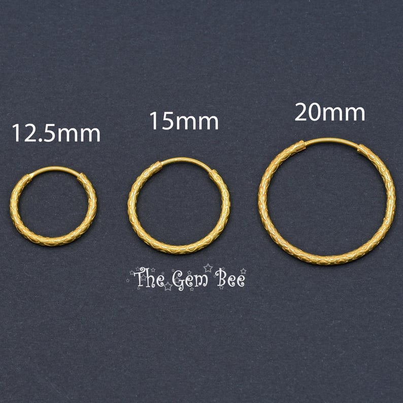 Puede incluir: Tres aros dorados con superficie texturizada, etiquetados con los tama&ntilde;os 12,5 mm, 15 mm y 20 mm. El texto The Gem Bee est&aacute; impreso debajo de los aros. Cada aro presenta una forma circular y un patr&oacute;n repetitivo en la banda de metal.