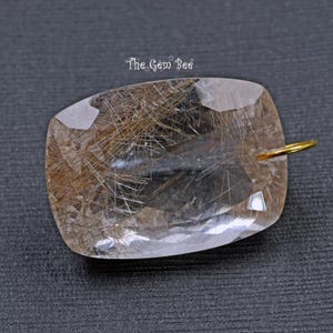 May include: A clear quartz pendant with a gold bail. The quartz has a lot of brown inclusions that look like hair.