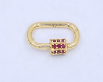 May include: An oval-shaped gold carabiner clasp featuring a rectangular sliding mechanism adorned with small, round, deep red rubies. The metal surface is polished and smooth, with the text 14K clearly engraved on the top section of the clasp.