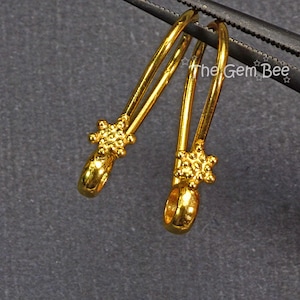 May include: A pair of gold-toned earring hooks with a star-shaped design at the end of each hook.