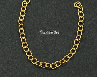May include: A gold-toned metal chain extender featuring a series of interconnected oval links. The text "The Gem Bee" is printed in white in the center of the curved chain. The chain is open at both ends, displaying a polished, reflective finish.