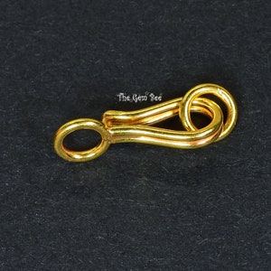 May include: Gold-toned metal clasp with a rounded loop on one end and a double loop on the other end.