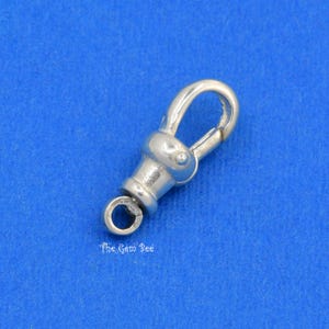 May include: A silver-colored swivel clasp with a rounded top and a small ring at the bottom. The clasp is designed to connect two items. The text "The Gem Bee" is printed on the bottom.