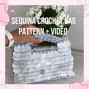 May include: A grey crocheted bag with white sequins, with the text "SEQUINA CROCHET BAG PATTERN + VIDEO." The bag is rectangular with a handle and is decorated with white sequins. A bouquet of white flowers is also visible in the image.