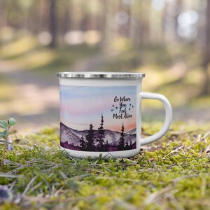 May include: White enamel camping mug featuring a watercolour mountain scene and the text "Go Where You Feel Most Alive".