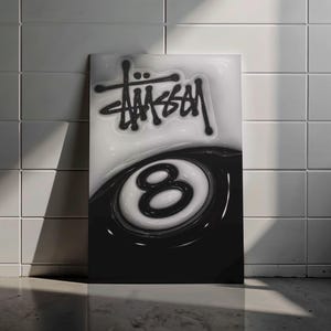 May include: Black and white artwork featuring the word "Stüssy" in a stylized font above a black and white eight ball. The artwork is leaning against a white tiled wall.