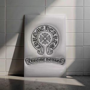 Pode incluir: Uma placa retangular branca com o logotipo Chrome Hearts em preto. O logotipo inclui um emblema circular com as palavras "Chrome Hearts" e um design floral. O nome da marca também é exibido em uma faixa abaixo.
