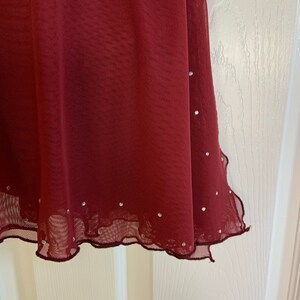 May include: A burgundy mesh skirt with a scalloped hem and silver rhinestones.