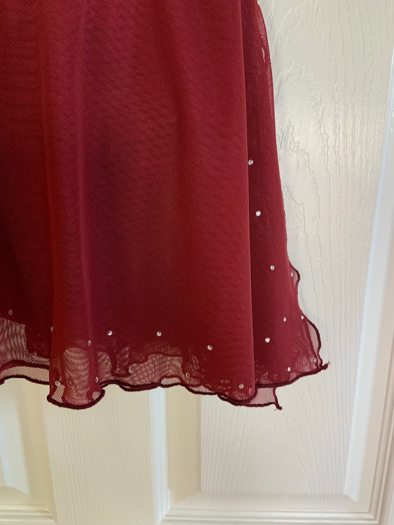 May include: A burgundy mesh skirt with a scalloped hem and silver rhinestones.