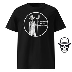 Op de afbeelding: Zwart T-shirt met een witte cirkelvormige afbeelding van een skeletboer die een hooivork vasthoudt. De tekst in de cirkel luidt "It ain't much but it's honest work."