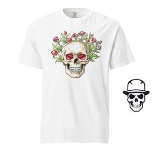 May include: White t-shirt featuring a skull design. The skull has red eyes and is surrounded by pink flowers.