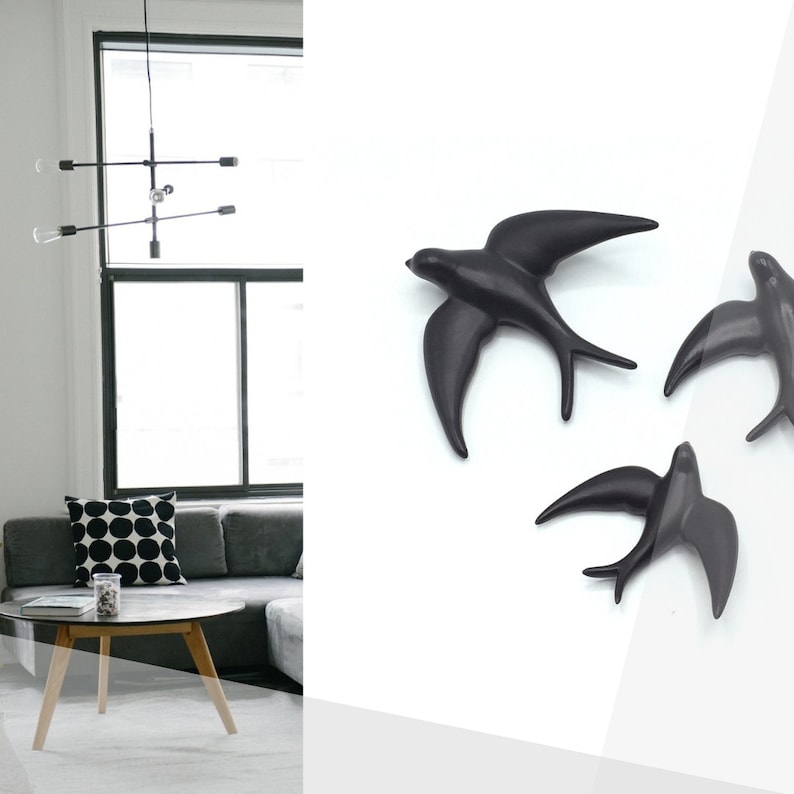 May include: Three black ceramic swallow wall sculptures in flight. The swallows are in various positions, with their wings spread out. The sculptures are on a white background.