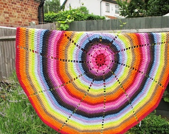 May include: A colorful crocheted round rug with a rainbow pattern. The rug is made of different colored yarn and has a circular design.
