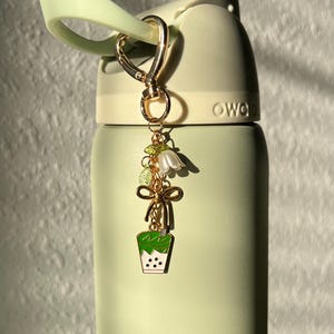 matcha bubble tea owala charm, matcha bubble tea charm with gold bow, green leaves, and a white flower. Matcha keychain