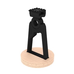 May include: Black 3D printed phone stand with a gear design and a wooden base.
